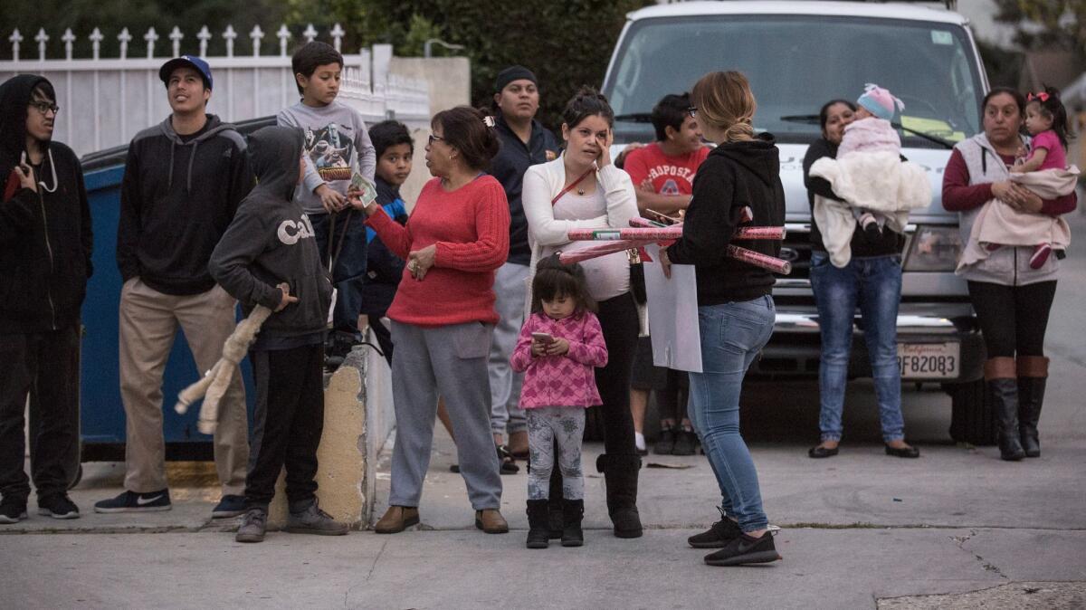 Neighbors watch as the LAPD investigates a body found in a shallow grave in Lennox.