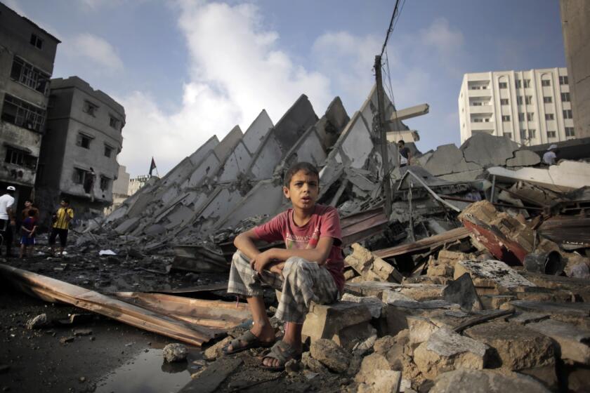 A Palestinian boy sits next to the rubble of what was a 15-story high-rise following Israeli airstrikes in Gaza City on Aug. 26.