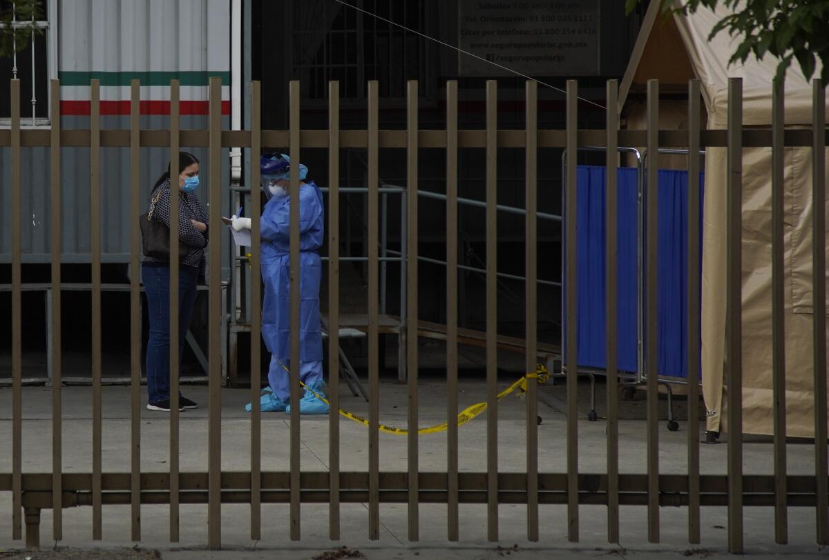 A woman is pre screened for COVID-19 by medical staff outside Hospital General Numero 1.