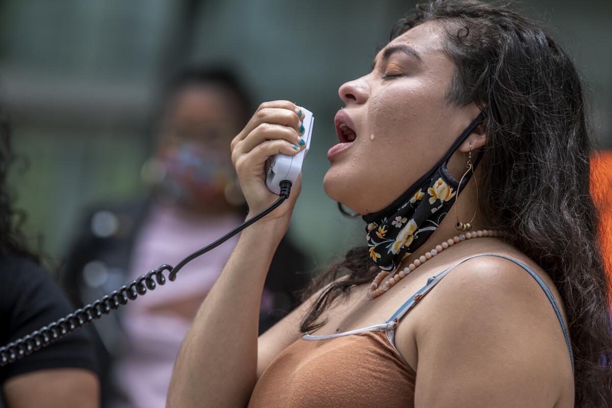 Claudia Rueda cries while speaking into a handheld device