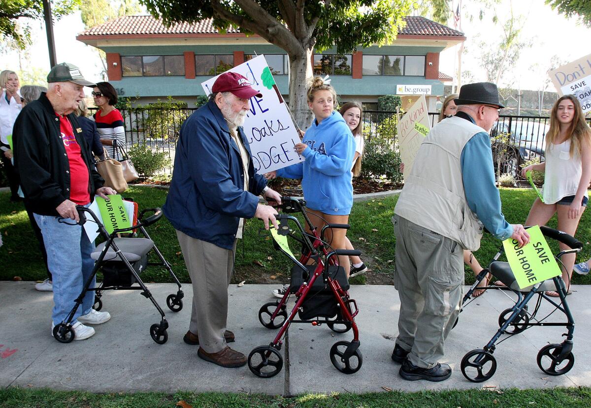 12 Oaks Lodge residents Bill Hughes, 93, John Meilan, 90, and Jim Davidson, 91, with the be.group building in the background, march in front of the business in Glendale, protesting the closing of their La Crescenta residence on Wednesday, Oct. 2, 2013.
