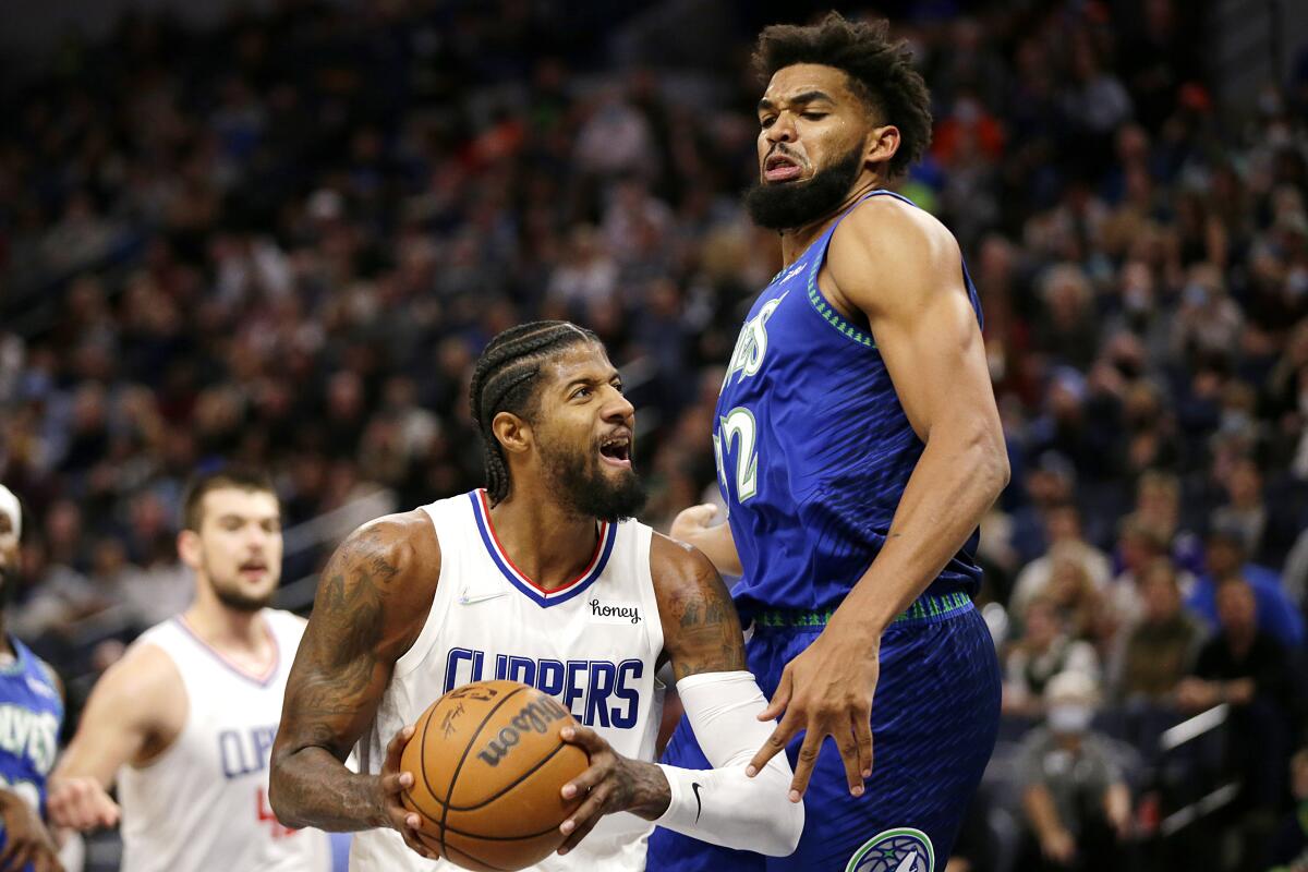 The Clippers' Paul George, left, looks to take a shot against the Timberwolves' Karl-Anthony Towns on Nov. 5, 2021.