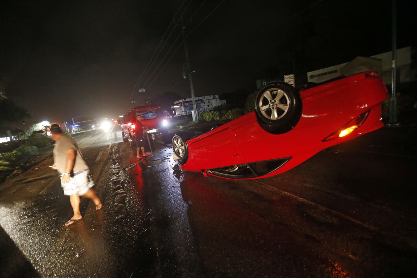 People tend to a car that flipped over on Cape Coral Parkway during Hurricane Irma, in Cape Coral, Fla., on Sept. 10, 2017.