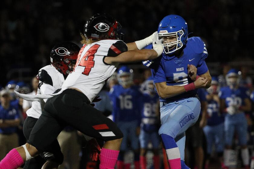NORCO, CA - OCTOBER 15, 2021: Norco quarterback Kyle Crum (9) gets poked in the eye after he releases the ball by Corona Centennial defender Demarieon Young in the first half at Norco High School on October 15, 2021 in Norco, California.(Gina Ferazzi / Los Angeles Times)
