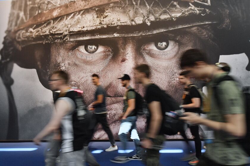 Visitantes pasan frente a un cartel publicitario del videojuego "Call of Duty" en la feria Gamescom en Colonia, Alemania, 22 de agosto de 2017. (AP Foto/Martin Meissner, File)