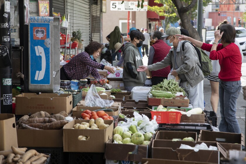 People browse boxes of produce on the sidewalk