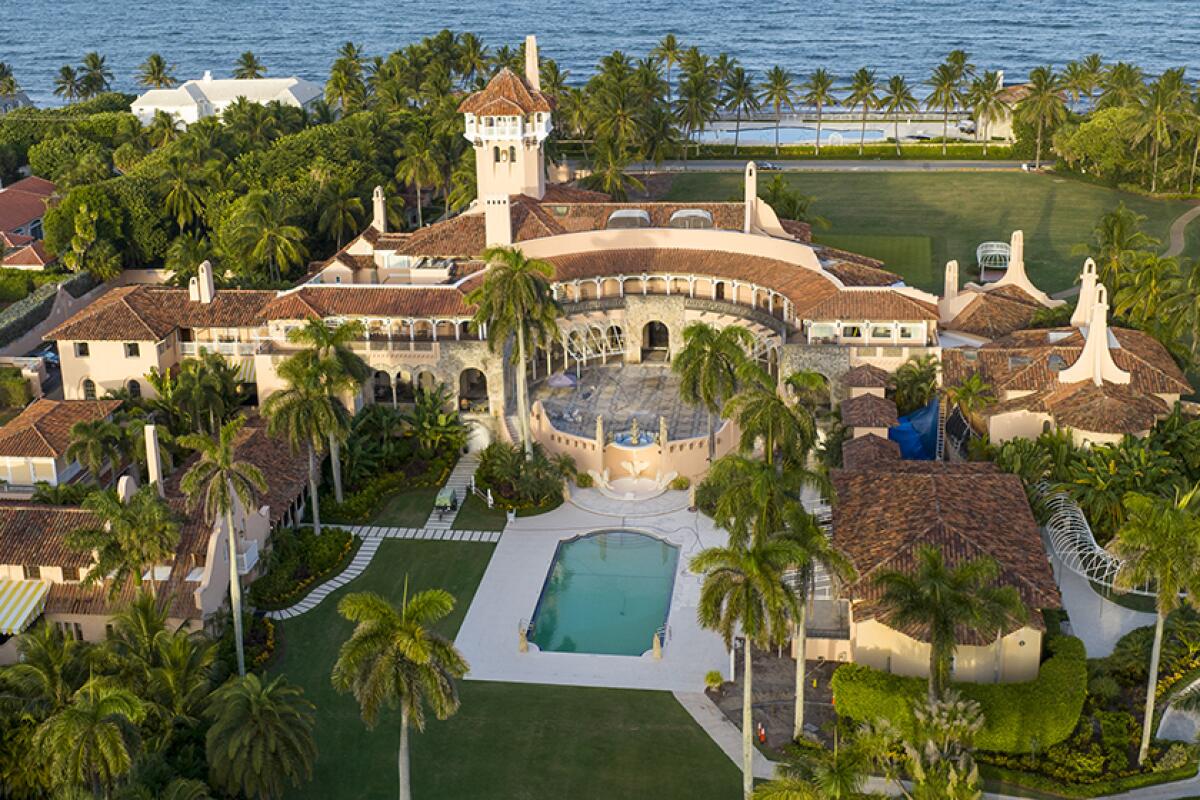 An aerial view of a large waterfront estate dotted with palm trees.