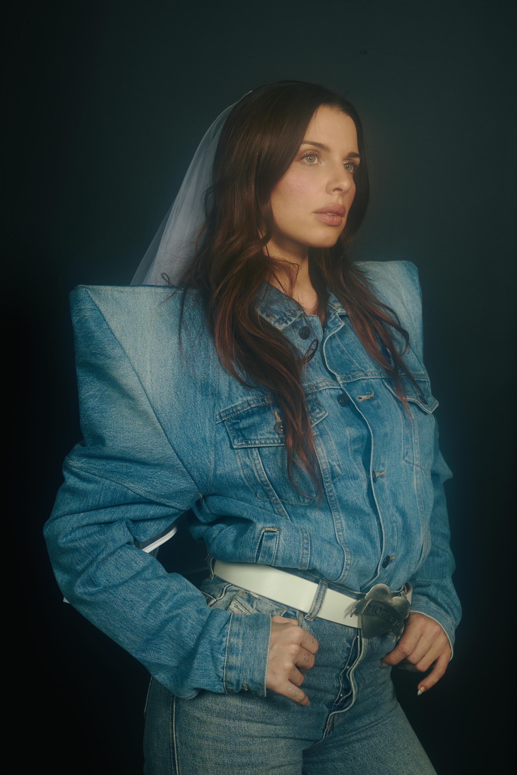 A woman in a denim jacket looks off camera.
