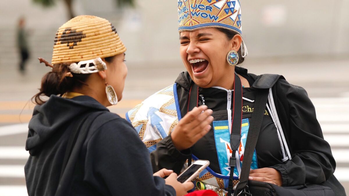 UC Riverside student Katianna Warren, right, laughs with Miztlayolxochitl Aguilera, a student at Cal State Long Beach, during festivities kicking off Indigenous People Day.