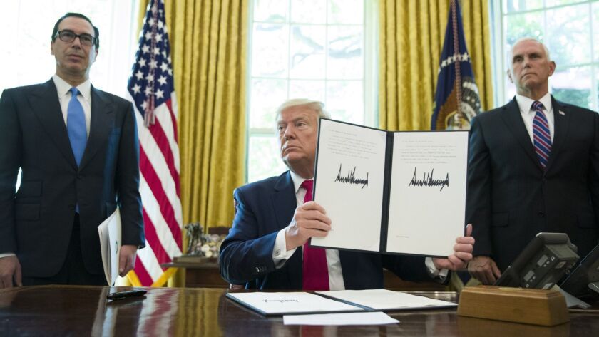 President Trump holds up a signed executive order to increase sanctions on Iran, flanked by Treasury Secretary Steven T. Mnuchin, left, and Vice President Mike Pence on June 24, 2019.