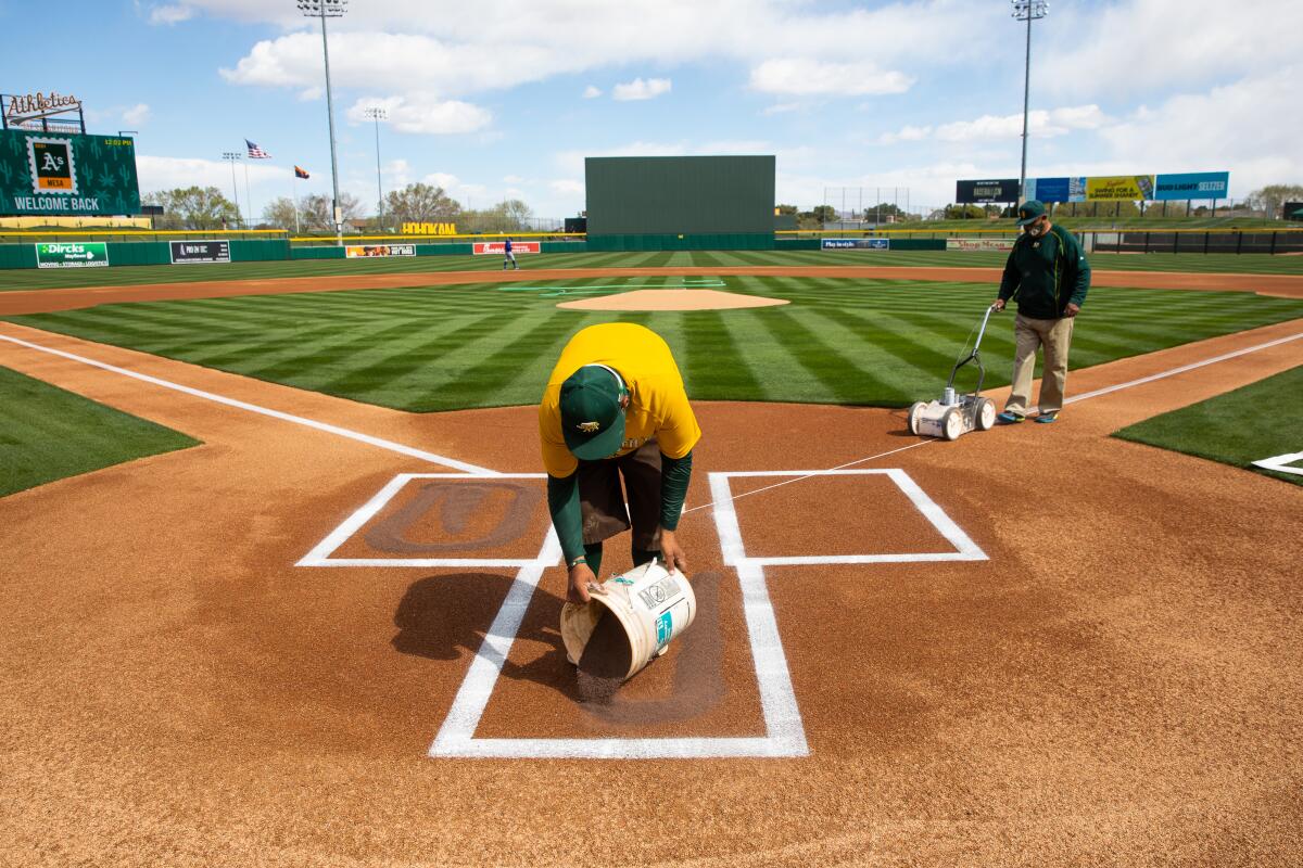 Members of the grounds crew prep the field at Hohokam Stadium, the spring home of the Oakland Athletics.