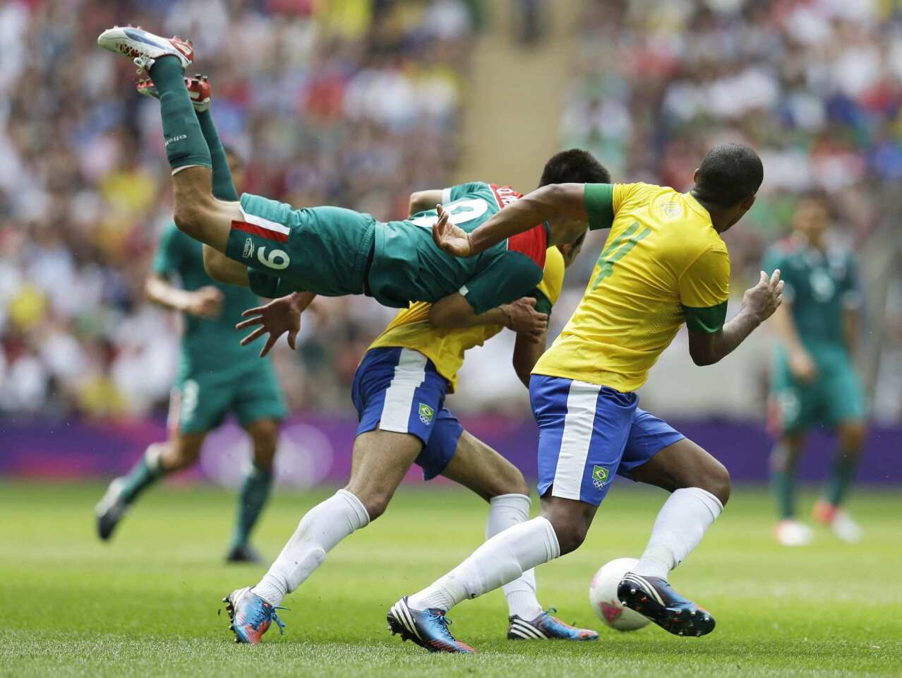 Mexico's Oribe Peralta goes airborne in front of Brazil's Juan Jesus, right, in the Olympic finals.