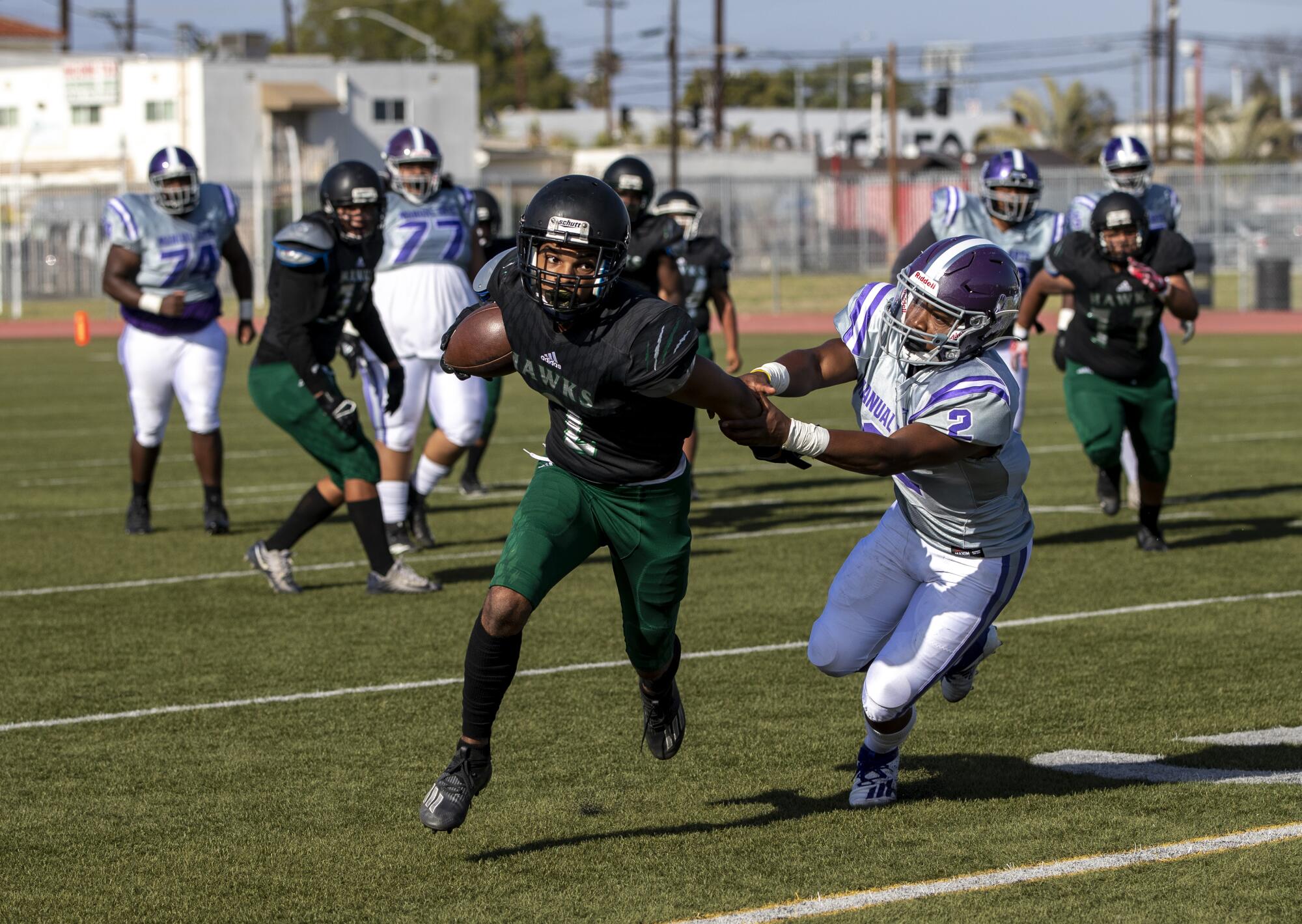 Hawkins wide receiver Myles Nash scampers for more yardage before he's tackled by Manual Arts defensive back Markeith Taylor.