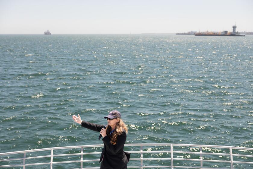 LONG BEACH, CA - May 20, 2026: Suzanne Plezia, managing director of engineering services at Port of Long Beach and Offshore Wind California board chair, points towards the Port of Long Beach's proposed Pier Wind project site, where floating offshore wind turbines will be assembled and deployed, during a boat tour with attendees of the 2026 Pacific Offshore Wind Summit join a boat tour on Wednesday, May 20, 2026. (Christina House / Los Angeles Times)