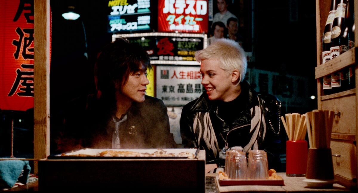 A man and a woman eat at a sushi bar.