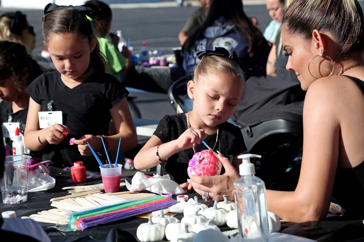 Natali, 6, center, her sister, Arlyn, 8, left, and their mother, Vickee, right, participate in a pumpkin decorating activity.