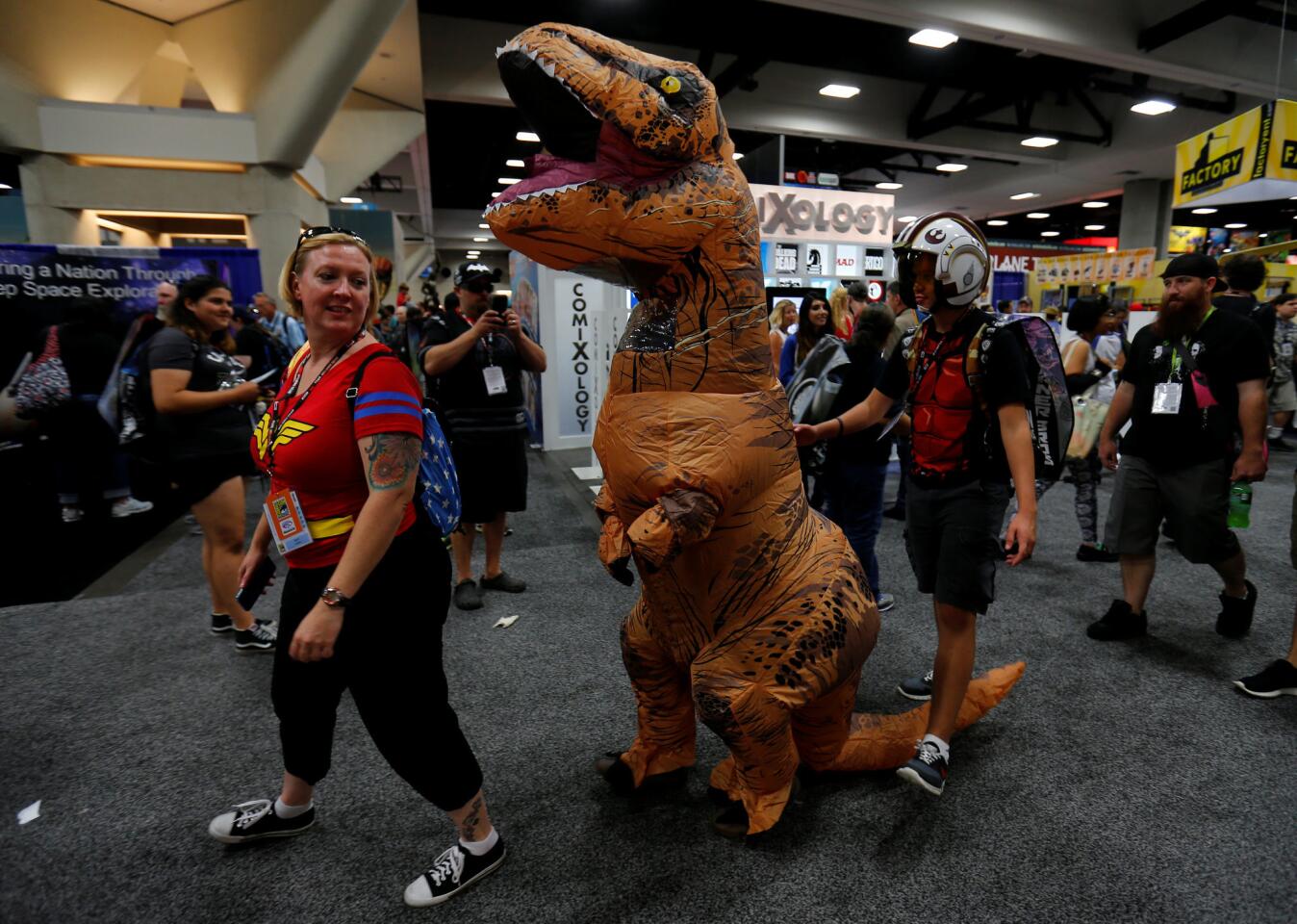 Fans of superhero movies, comic books and pop culture walk the convention floor in costume during the opening day of Comic-Con International in San Diego