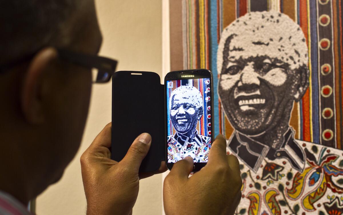 A visitor uses his phone to take a photo of one of the posters on display at an exhibition celebrating Nelson Mandela's 95th birthday at the University of Pretoria in South Africa.