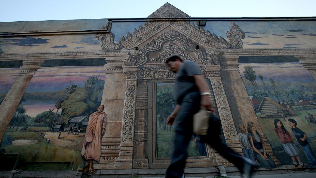 A man walks past a mural depicting the life of Cambodians just off Anaheim Street in Long Beach, Calif. on July 14, 2017.