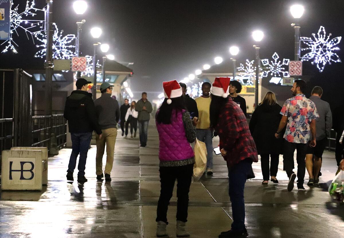 People walk up and down the pier enjoying the lights during Huntington Beach's annual Light a Light of Love ceremony.