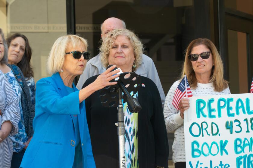 Retired Huntington Beach librarian Barbara Richardson and Protect Huntington Beach co-founder Cathey Ryder join about a dozen concerned citizens calling for a measure repealing a children's book review board recently approved by the City Council on Wednesday, April 17, 2024.