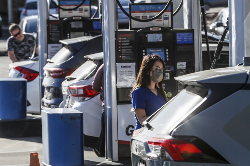 People fill their cars at a gas station.