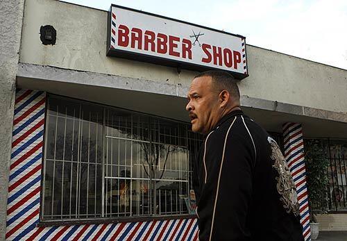 Carlos Arena stands outside the Barber Shop in the 1200 block of Rosecrans Avenue in Compton after a triple murder in an apartment behind the shop Sunday.