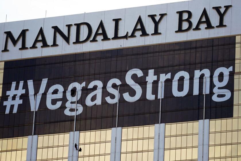 FILE - In this Oct. 16, 2017, file photo, workers install a #VegasStrong banner on the Mandalay Bay hotel and casino in Las Vegas. The official slogan of Las Vegas, "What happens here, stays here," is back by popular demand. The destination's tourism agency revived the 15-year-old slogan this week, three months after it was put on hold following the October mass shooting. Stephen Paddock opened fire from the hotel on an outdoor country music concert, killing 58 and injuring hundreds. (AP Photo/John Locher, File)