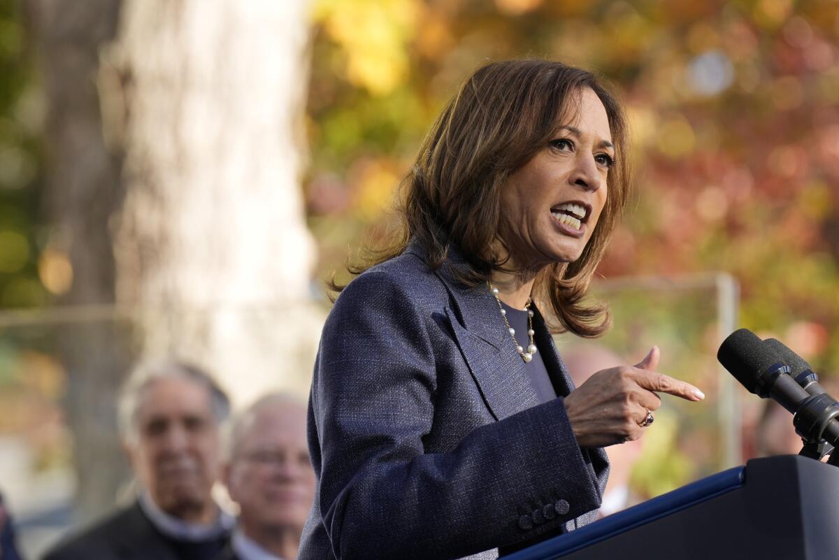 Kamala Harris points and speaks at a microphone.