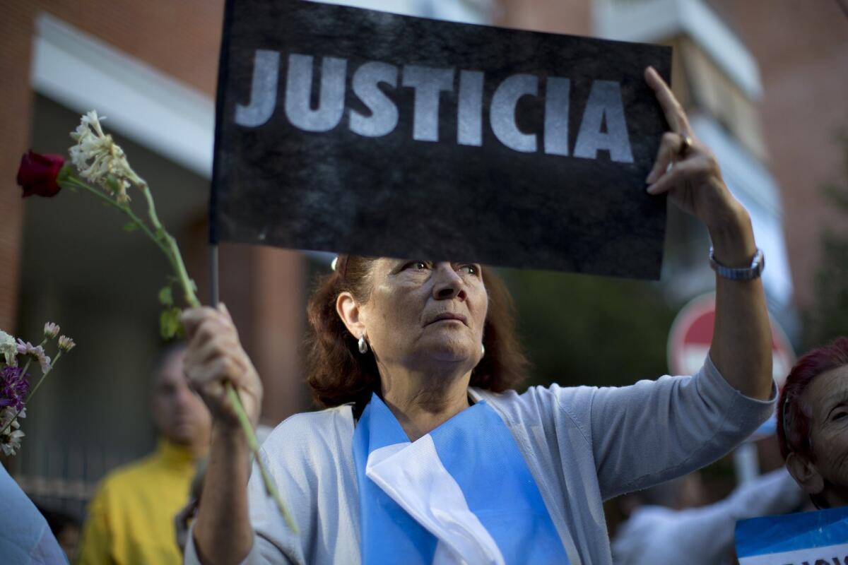A woman holds up a "Justice" sign with others outside the funeral home where a private wake was held for prosecutor Alberto Nisman in Buenos Aires.