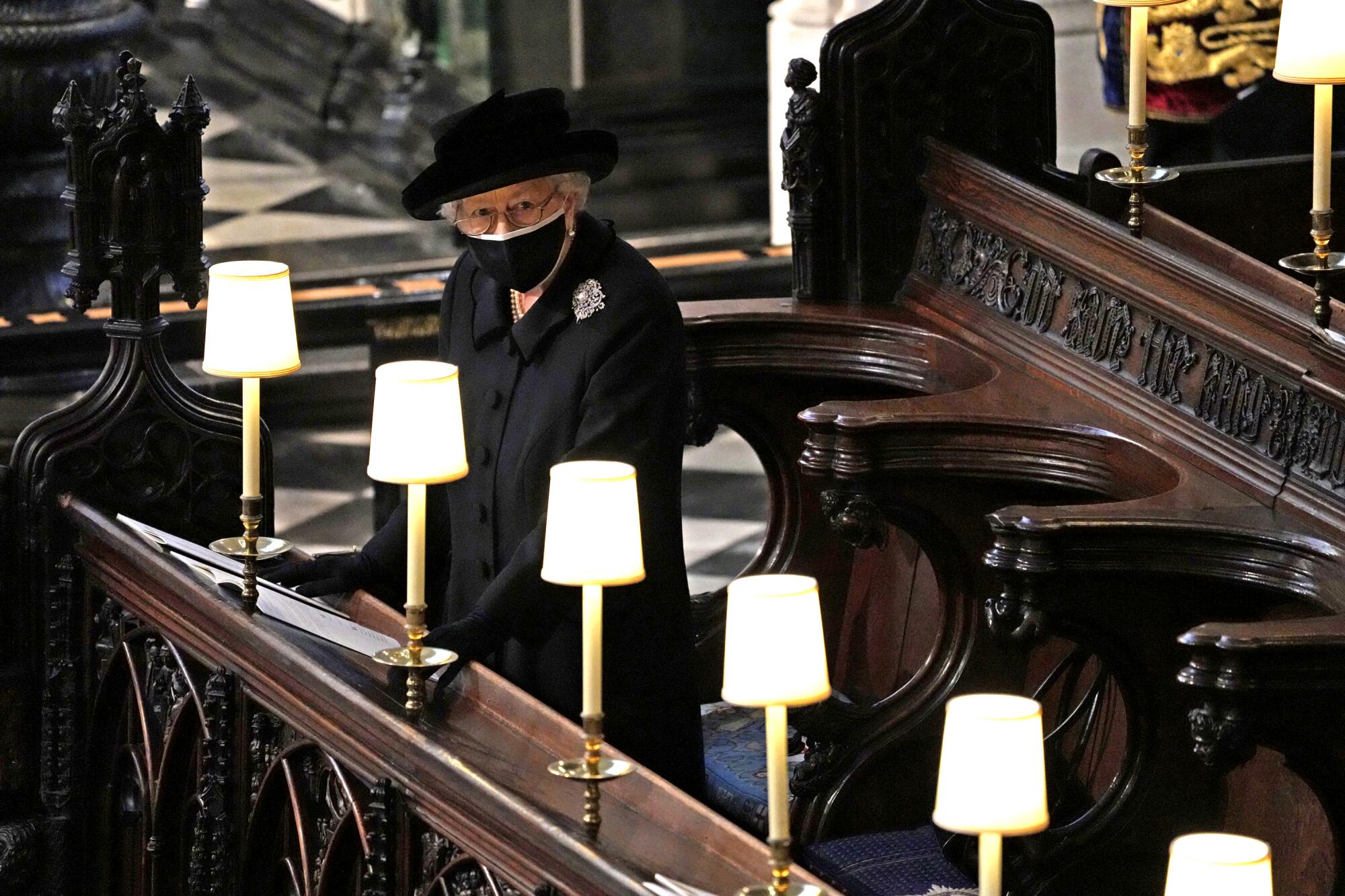 Queen Elizabeth II stands in a pew in St. George’s Chapel during the funeral