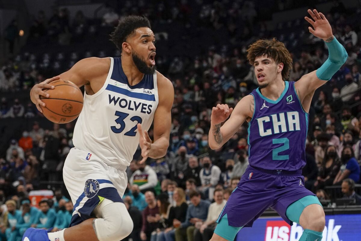 Minnesota Timberwolves center Karl-Anthony Towns (32) drives past Charlotte Hornets guard LaMelo Ball (2) during the first half of an NBA basketball game Tuesday, Feb. 15, 2022, in Minneapolis. (AP Photo/Craig Lassig)