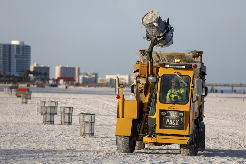 Un trabajador municipal vacía botes de basura en preparación para la llegada de una tormenta en Clearwater Beach el sábado 3 de agosto de 2024, en Clearwater, Florida. (Jefferee Woo/Tampa Bay Times vía AP)