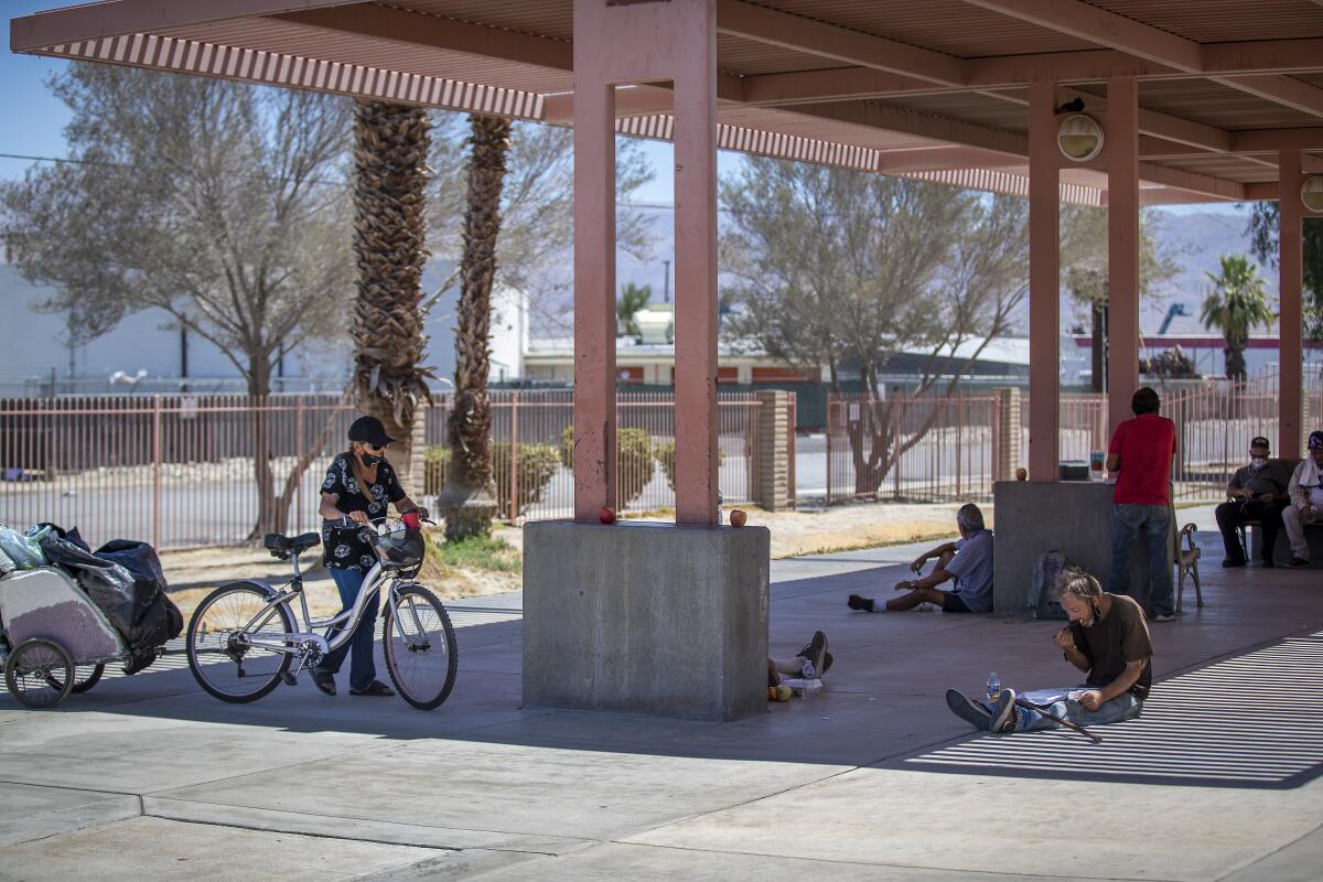 Homeless people sit in the shade.