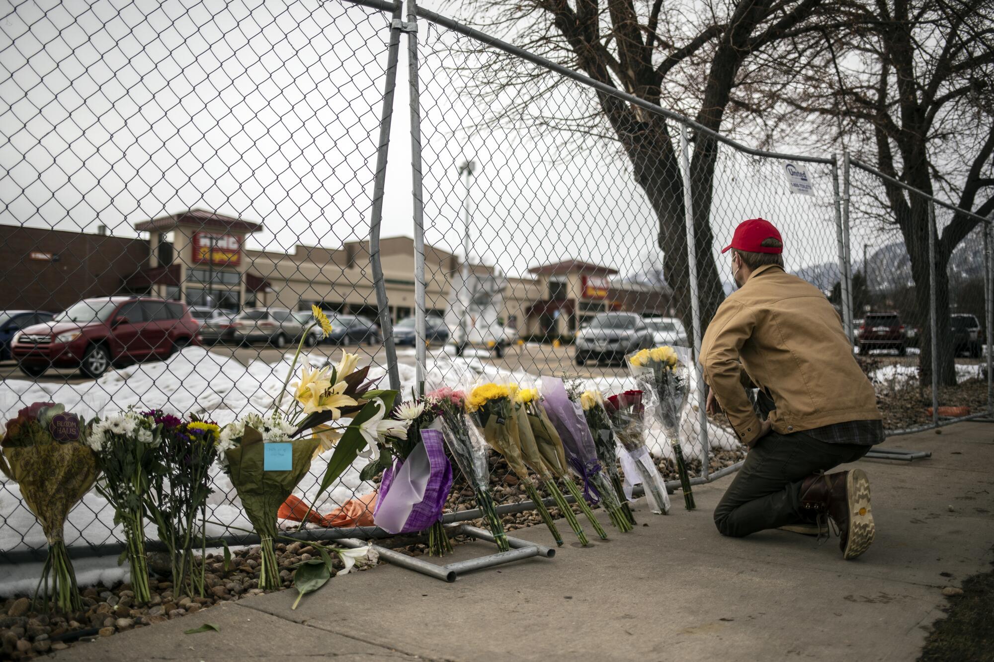 A mourner leaves flowers at a fence around the King Soopers grocery store.