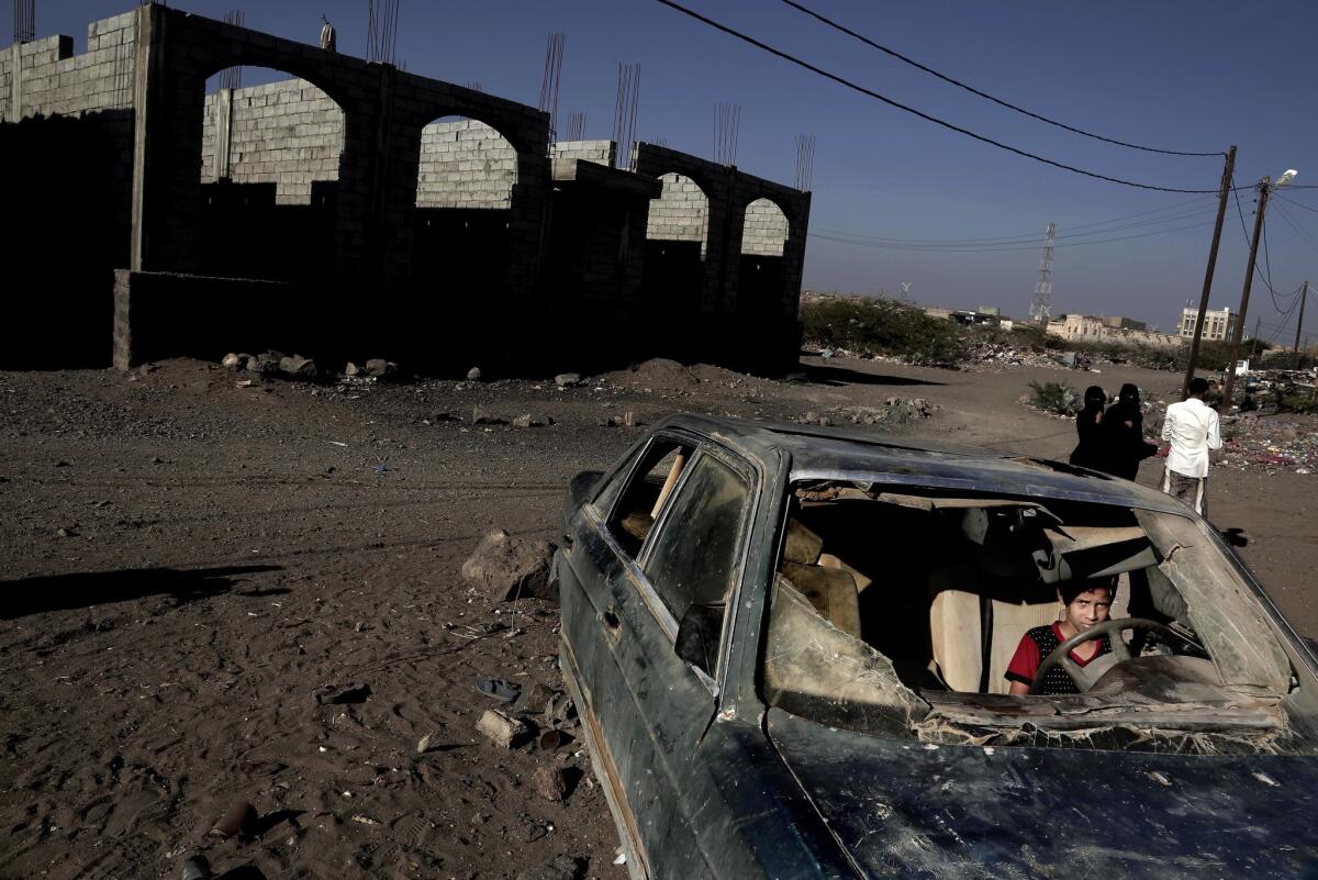 A boy sits in a car damaged during the ongoing three year conflict in Mocha, Yemen.