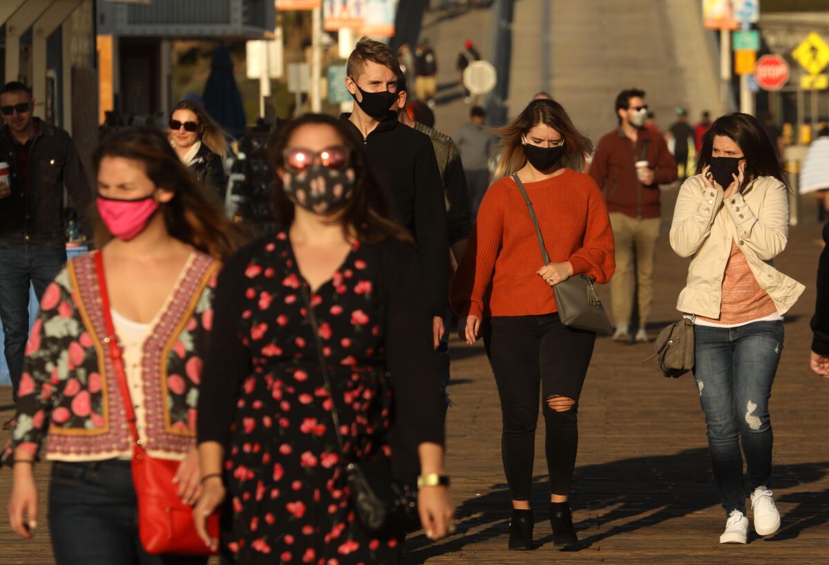 People, most wearing masks, walk on the Santa Monica Pier on Monday.