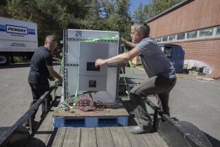 Henry Kovacs, left, and Hayden Wilson, right, volunteers with the Footprint Project, load two Tesla Powerwall batteries to deliver to communities impacted by Hurricane Helene in Mars Hill, N.C. on Oct. 9, 2024. (AP Photo/Gabriela Aoun Angueria)