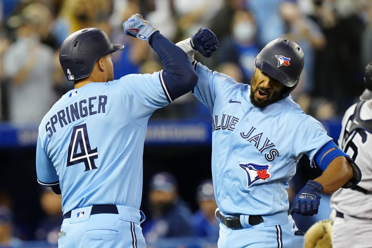 Toronto Blue Jays second baseman Marcus Semien, right, celebrates his home run against New York Yankees starting pitcher Gerrit Cole with teammate center fielder George Springer (4) during the first inning of baseball game in Toronto on Wednesday, Sept. 29, 2021. (Frank Gunn/The Canadian Press via AP)