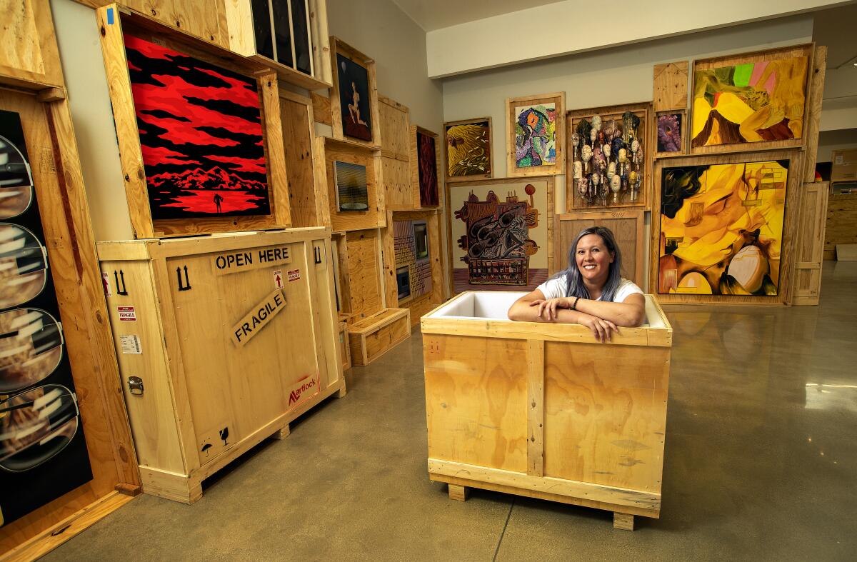 Kathy Grayson sits in a crate surrounded by paintings at a gallery in Los Angeles.