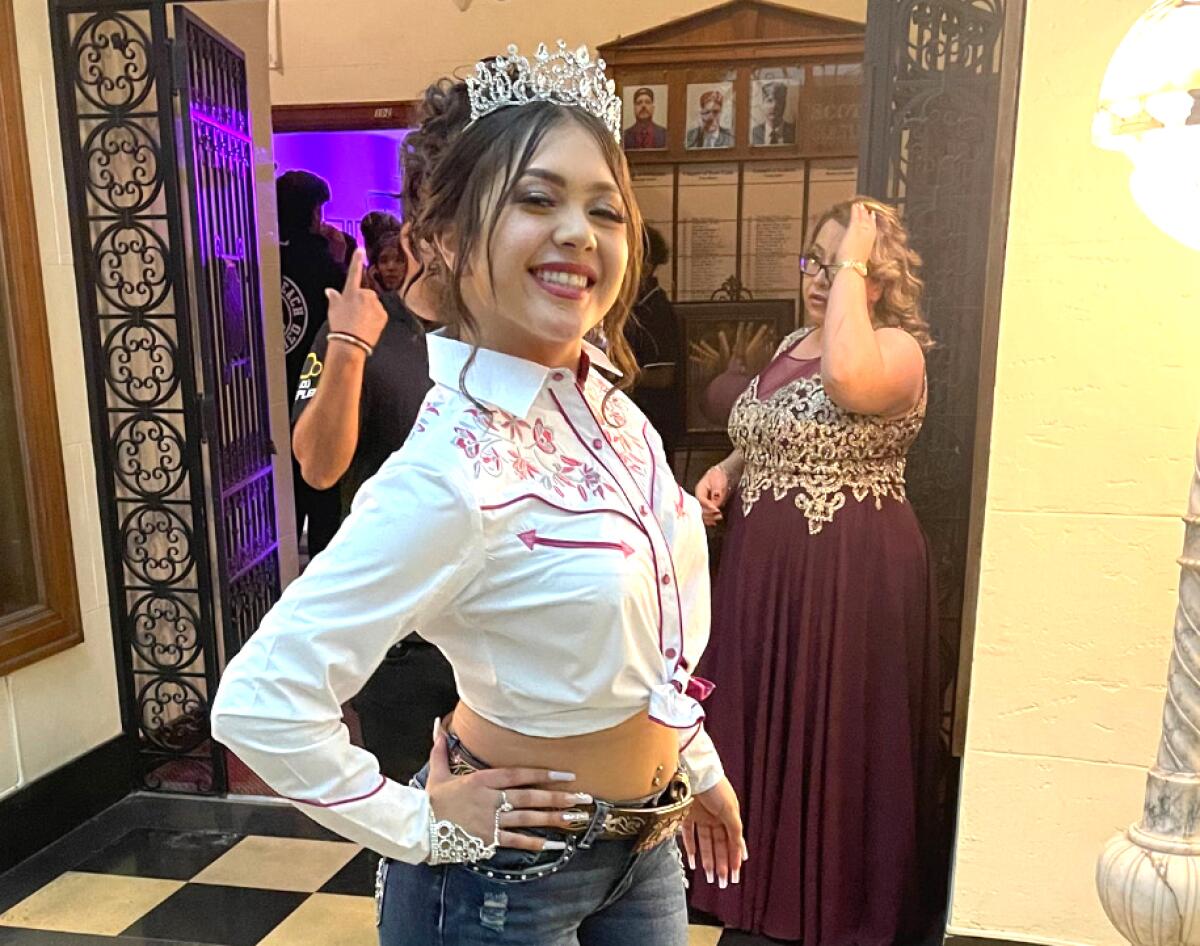 A teenage girl smiles while wearing a tiara.