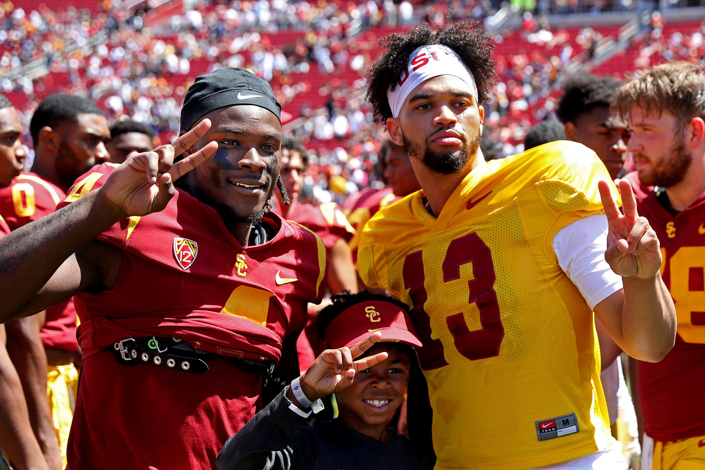 USC wide receiver Mario Williams, left, and USC quarterback Caleb Williams with a young fan.