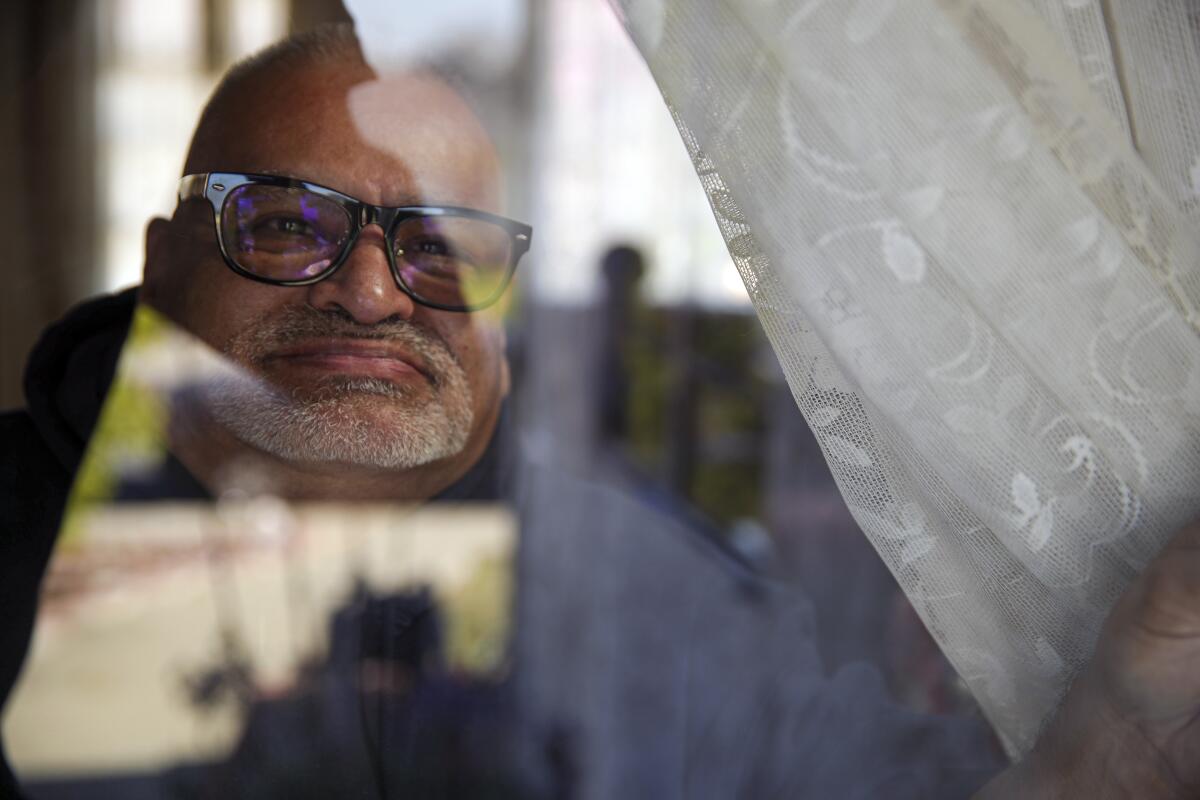 Luis Parocua looks outside the window at his home in Monterey Park.
