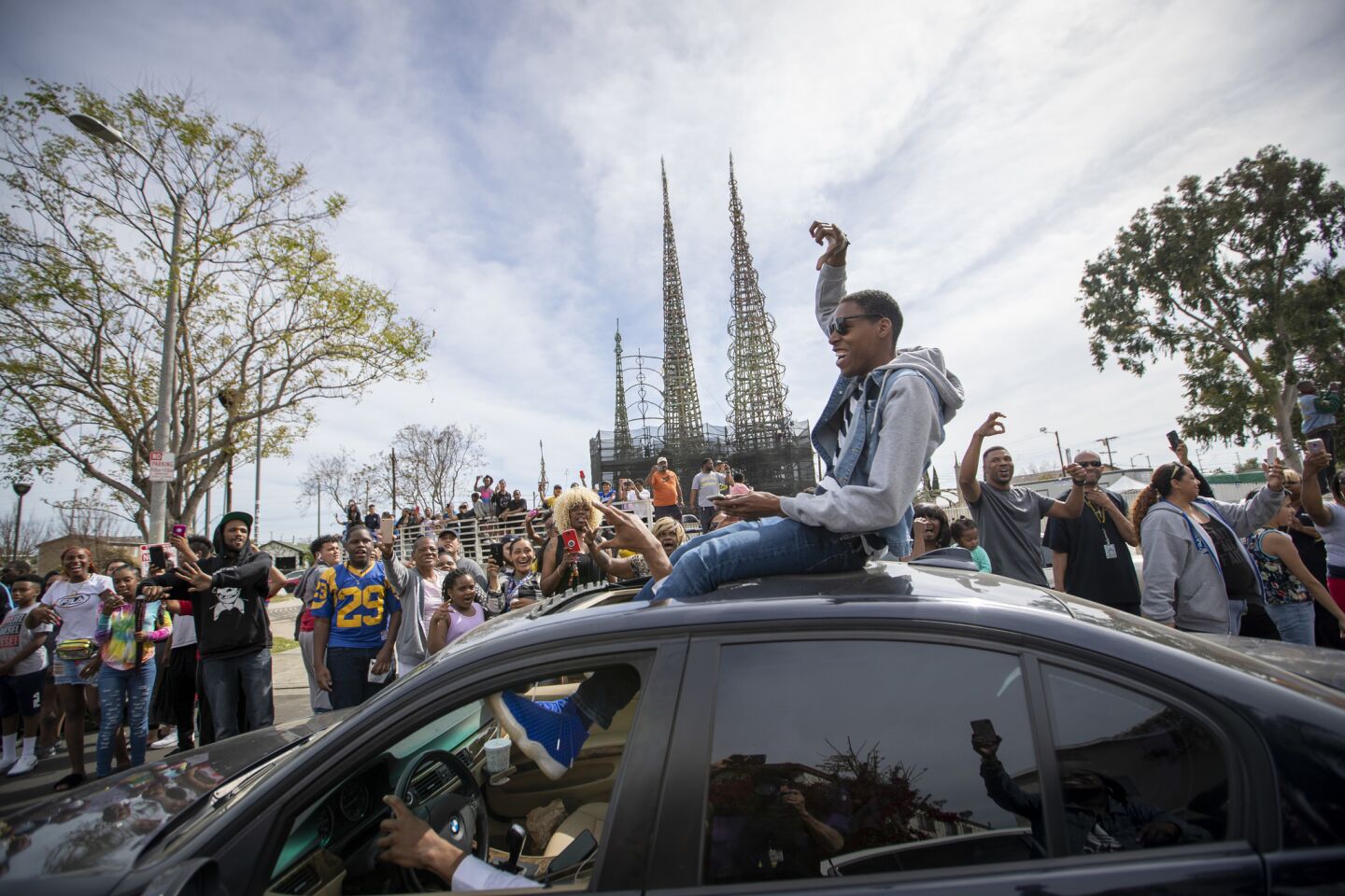 People celebrate the life of Nipsey Hussle as his funeral procession passes the Watts Towers.