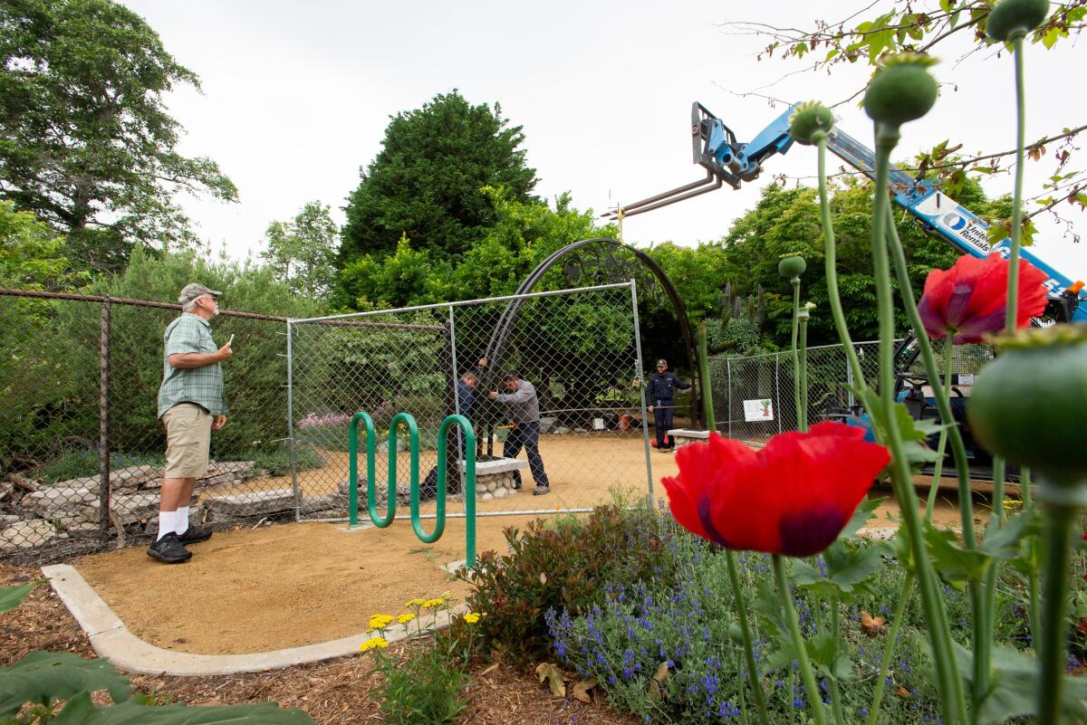 Steve Engels, left, watches a crew install a new archway at the Secret Garden in Huntington Central Park Friday.