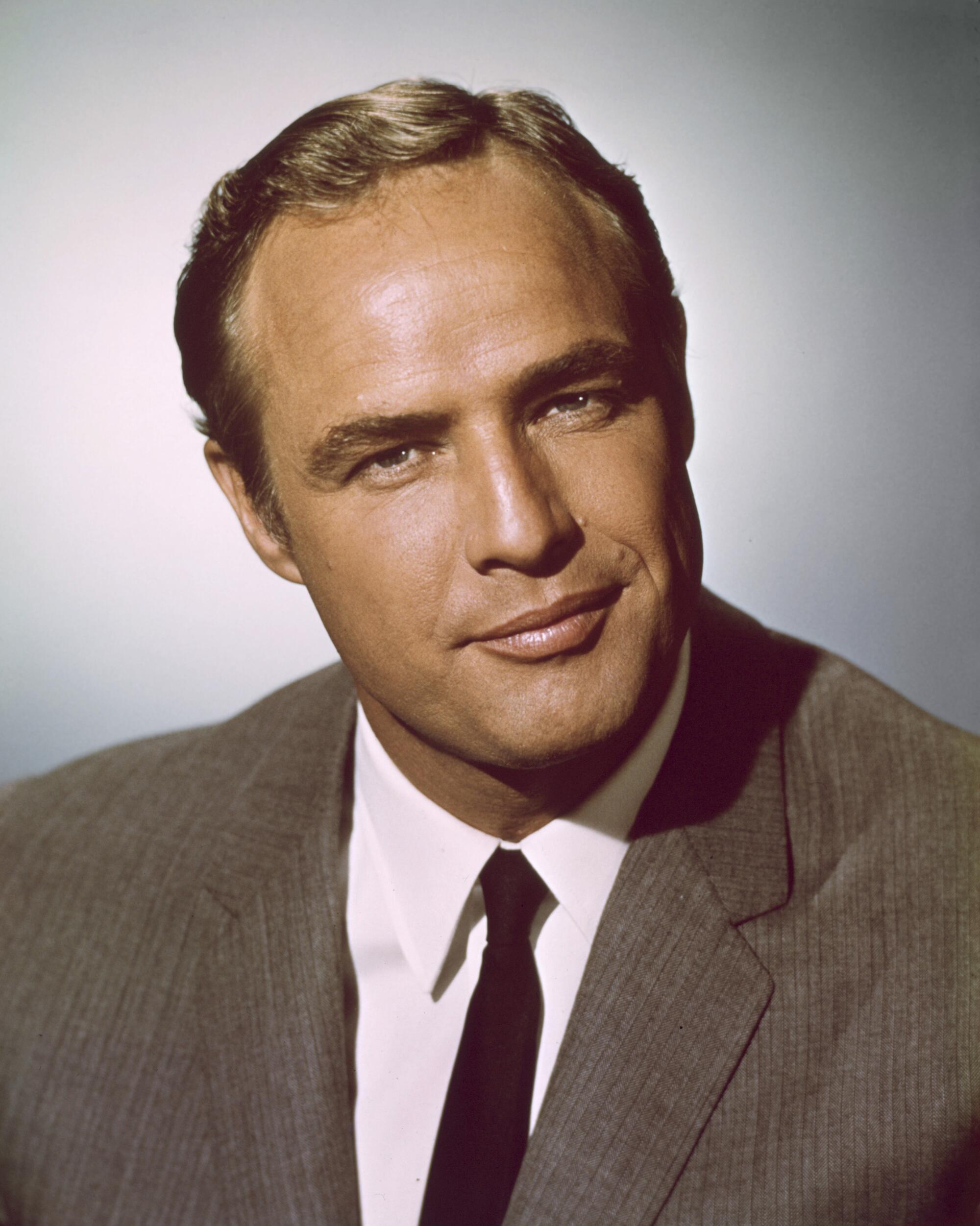 Actor Marlon Brando, in a brown suit jacket and tie, with a slight smile