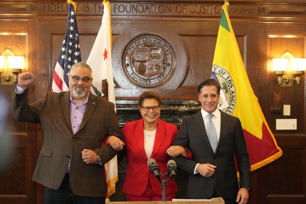 SEIU Local 99 Executive Director Max Arias, left, Los Angeles Mayor Karen Bass and District superintendent Alberto Carvalho lock in arms after announcing on a new contract together in Los Angeles City Hall Friday, March 24, 2023. The Los Angeles Unified School District and union leaders say they have reached a deal on a new contract for workers after a strike that shut down the nation's second-largest school system for three days. (AP Photo/Damian Dovarganes)