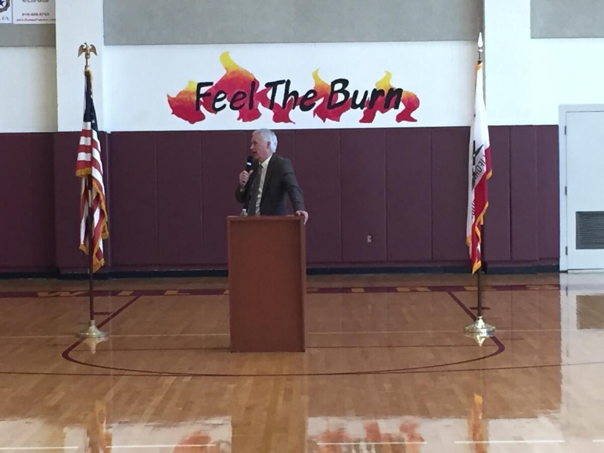 In Foresthill, Calif., Rep. Tom McClintock stands in front of the high school motto, which refers to the school's Wildfires mascot but calls to mind Democrat Bernie Sanders' presidential campaign.