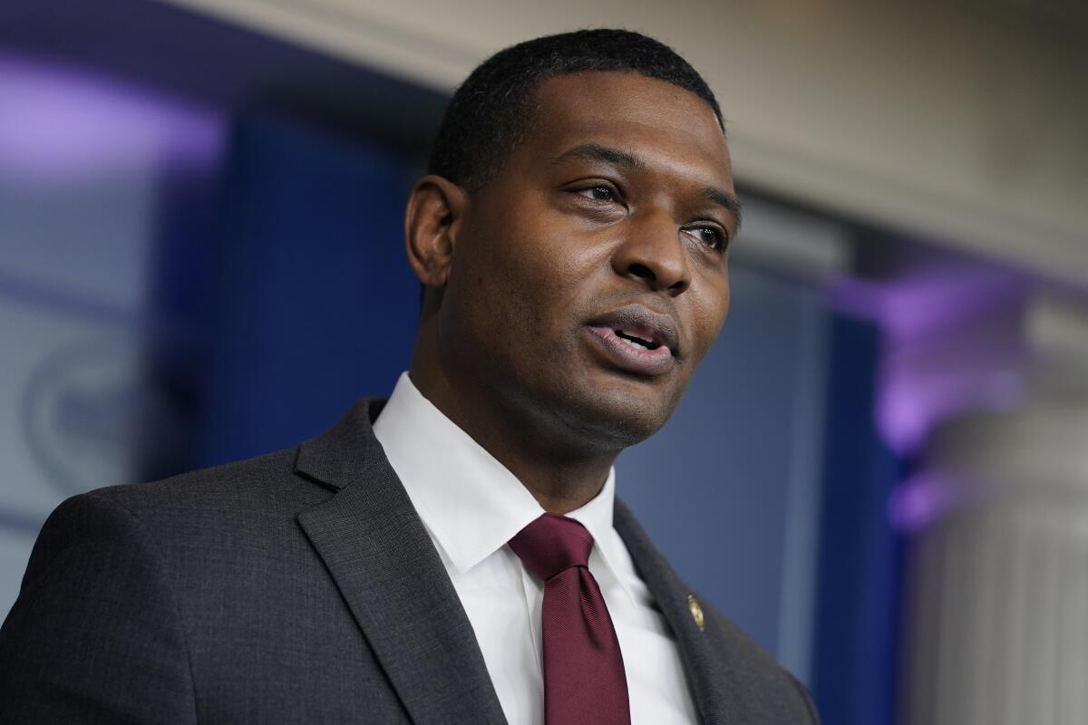 A man in a suit and red tie speaks 