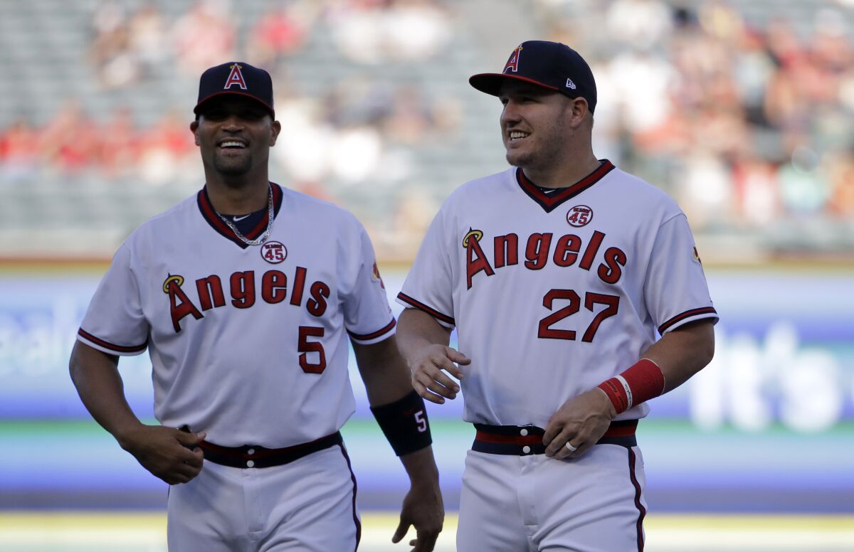 The Angels' Mike Trout, right, and Albert Pujols smile before a game against the Chicago White Sox on Aug. 17, 2019.